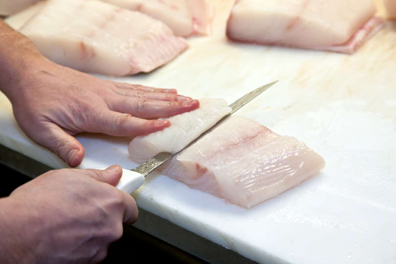 A master slices Halibut into serving sized portions with fish fillet knife