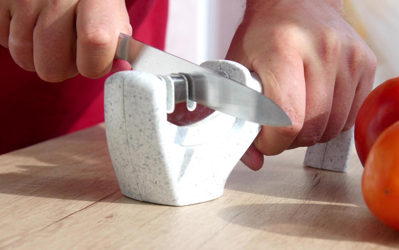 Manual sharpening of a knife in a sharpener in a kitchen