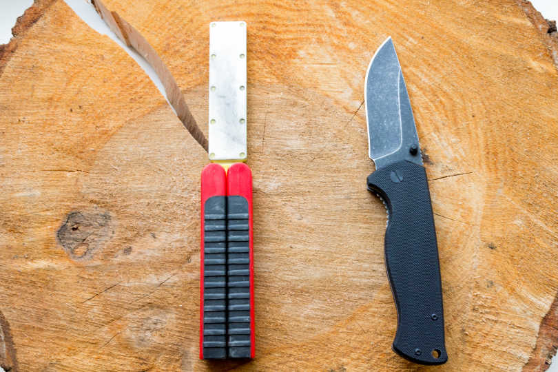 Set out a pocket knife and a pocket knife sharpener on a board