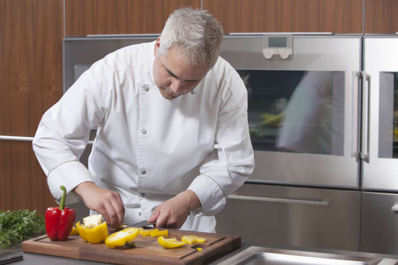 Chef cutting vegetable on end grain cutting board