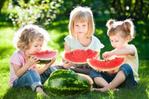 Group of happy children eating watermelon