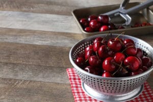 Removing pits from cherries in colander