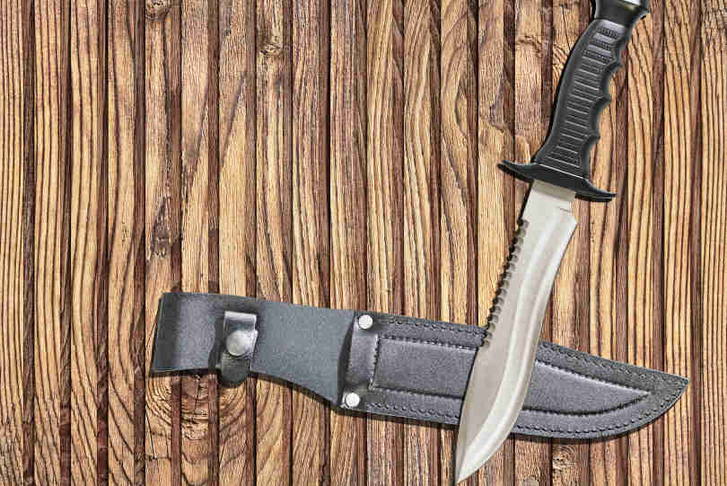 Bowie Knife with black leather knife guard on knotted pinewood