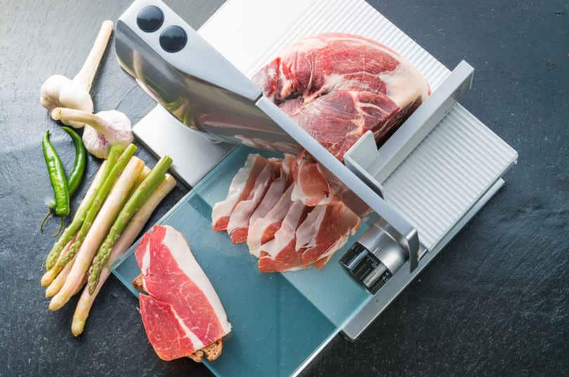 Slicing meat with a meat slicer on a table