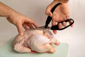 Cutting of chicken with shears on cutting board