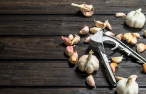 Garlic and garlic press. On wooden background