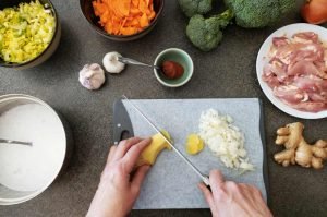 Chef cutting vegetables and meat on a heat resistant cutting board