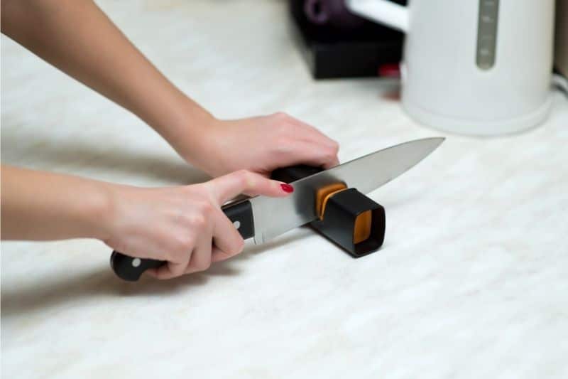 Woman sharpening a knife with a knife sharpener