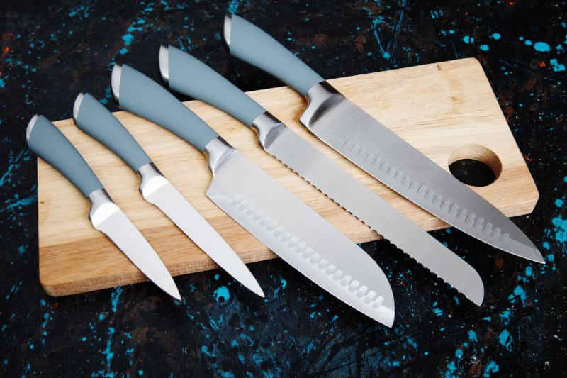 Set of five kitchen knives on wooden board