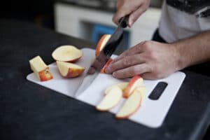 Man cutting apples on a plastic cutting board with a knife