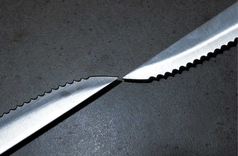 Serrated kitchen knives on the dark gray concrete table