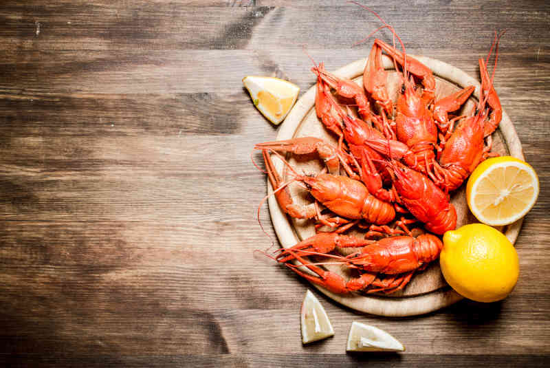 Boiled lobsters with slices of lemon on wooden board