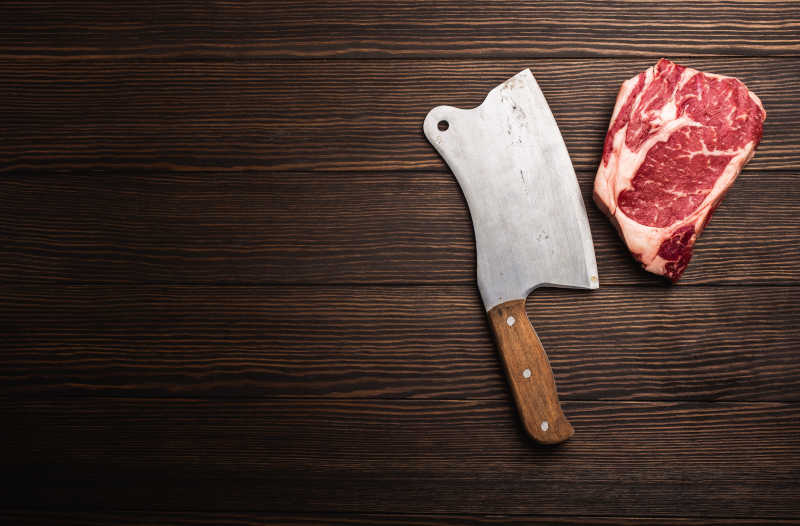 Raw fresh marbled meat steak Ribeye with rustic meat cleaver on wooden background