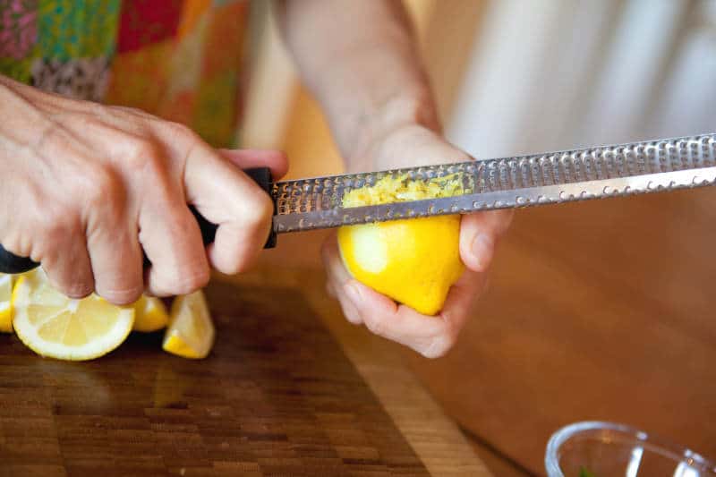 Woman holding a zester and making lemon zest