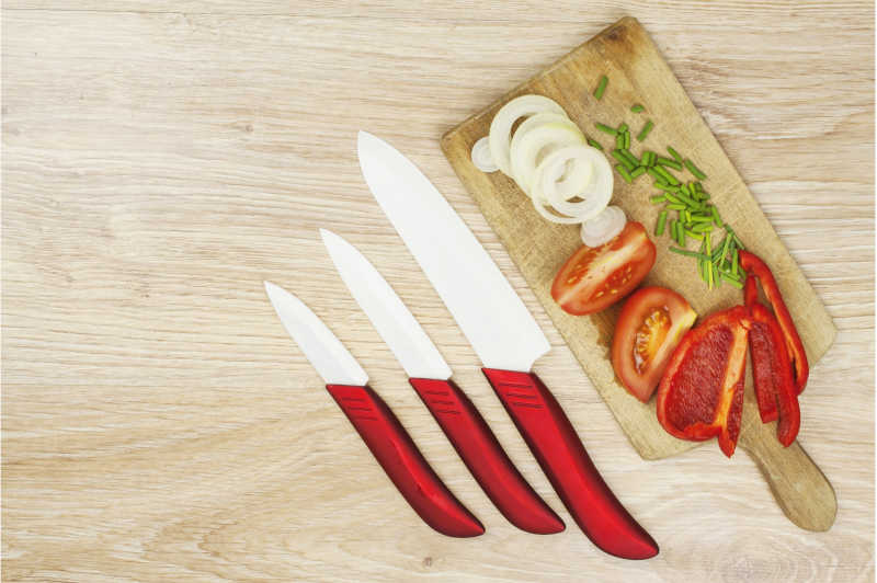 A set of paring knives and vegetable for salad on wooden board