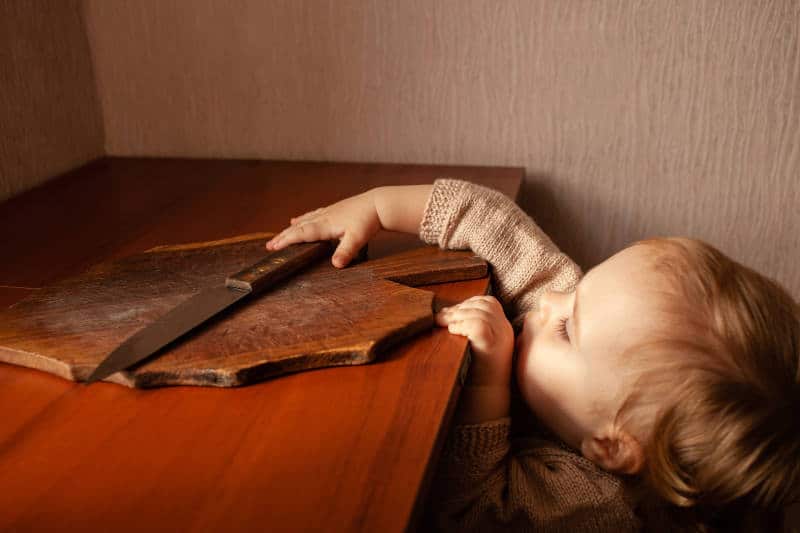 The child pulls a knife from the table.