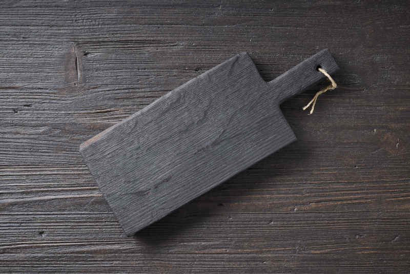 Black empty wood cutting board on dark kitchen table